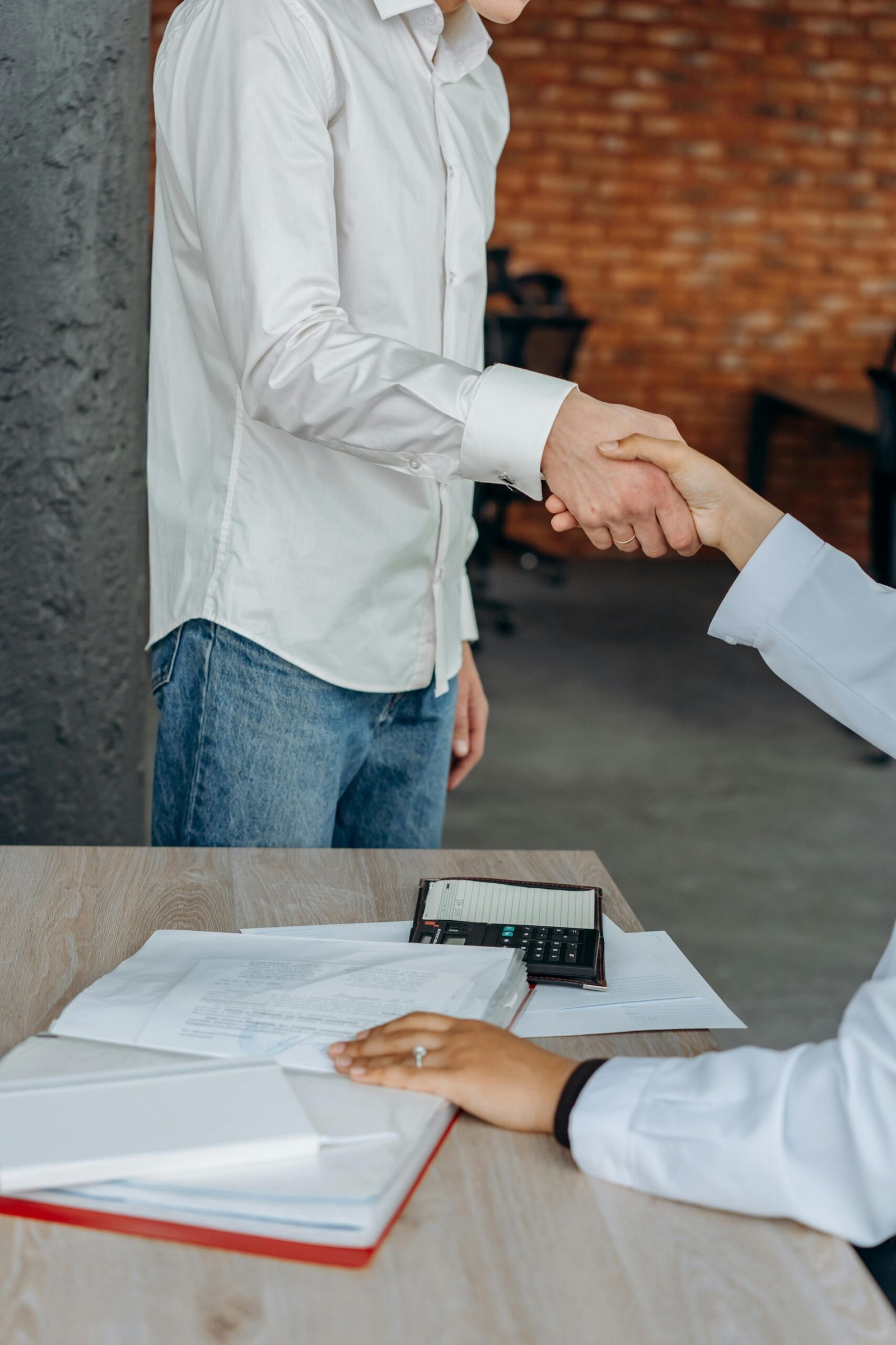 Two professionals shaking hands in a modern office, symbolizing agreement and teamwork.